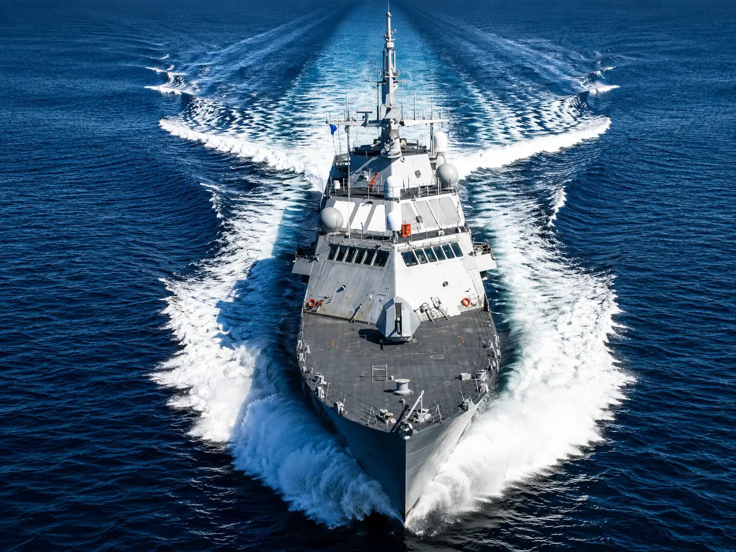 Naval warship cutting through deep blue ocean water